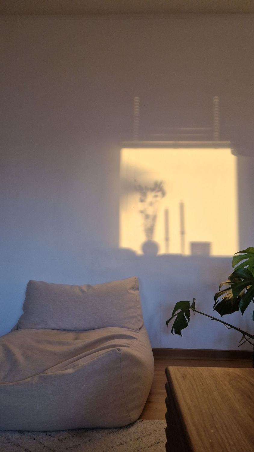 A soft white bean bag chair in a quiet room with warm window light on the wall