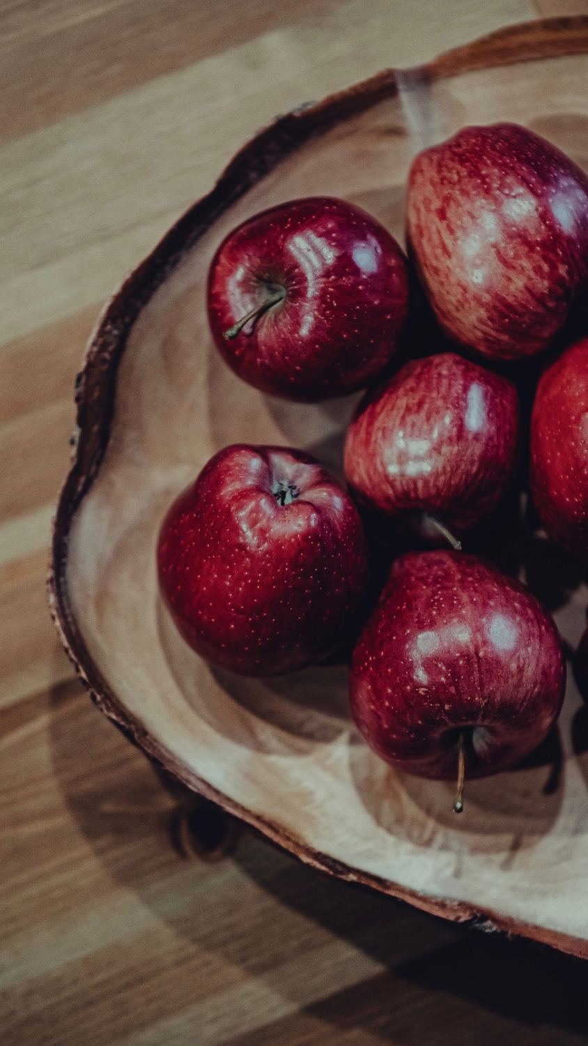 Shiny red apples in a wooden bowl