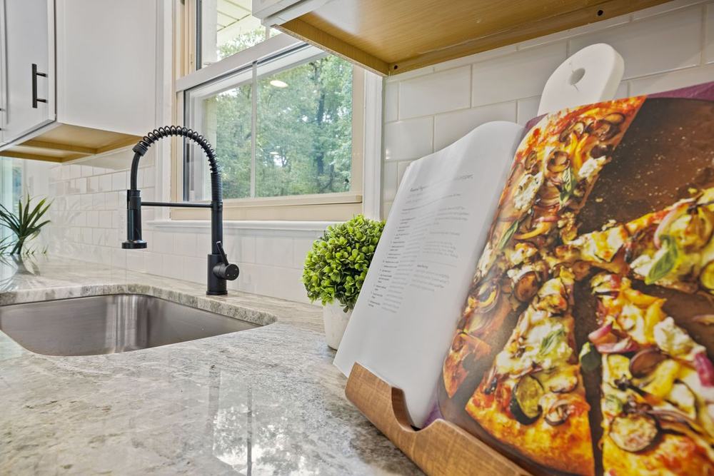 An open cookbook on a wooden stand on a kitchen counter