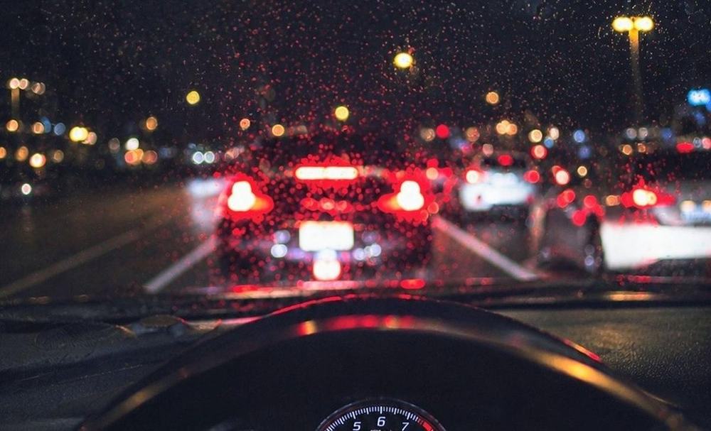 Evening traffic through a rainy windshield