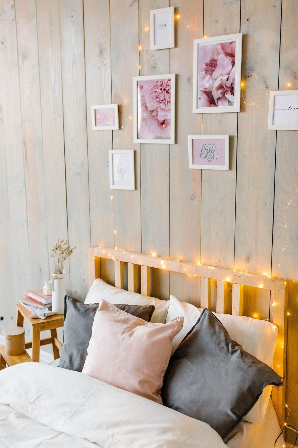 Cozy bedroom with warm white fairy lights on a wooden headboard and a gallery wall