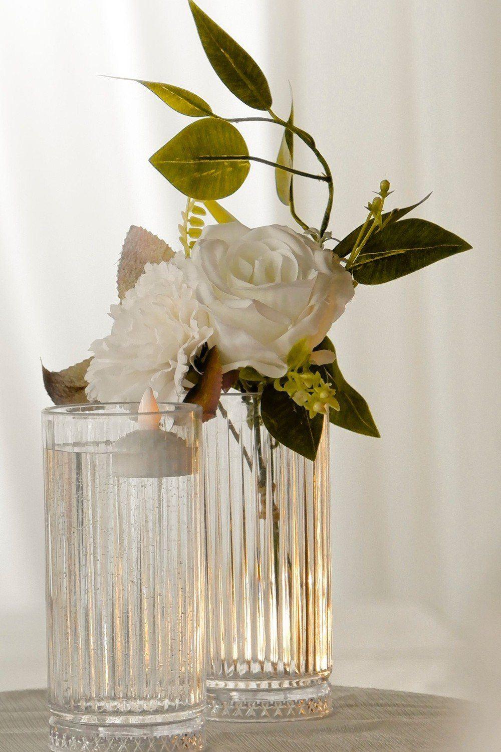 Fluted glass vases with a white rose and a floating flameless tealight