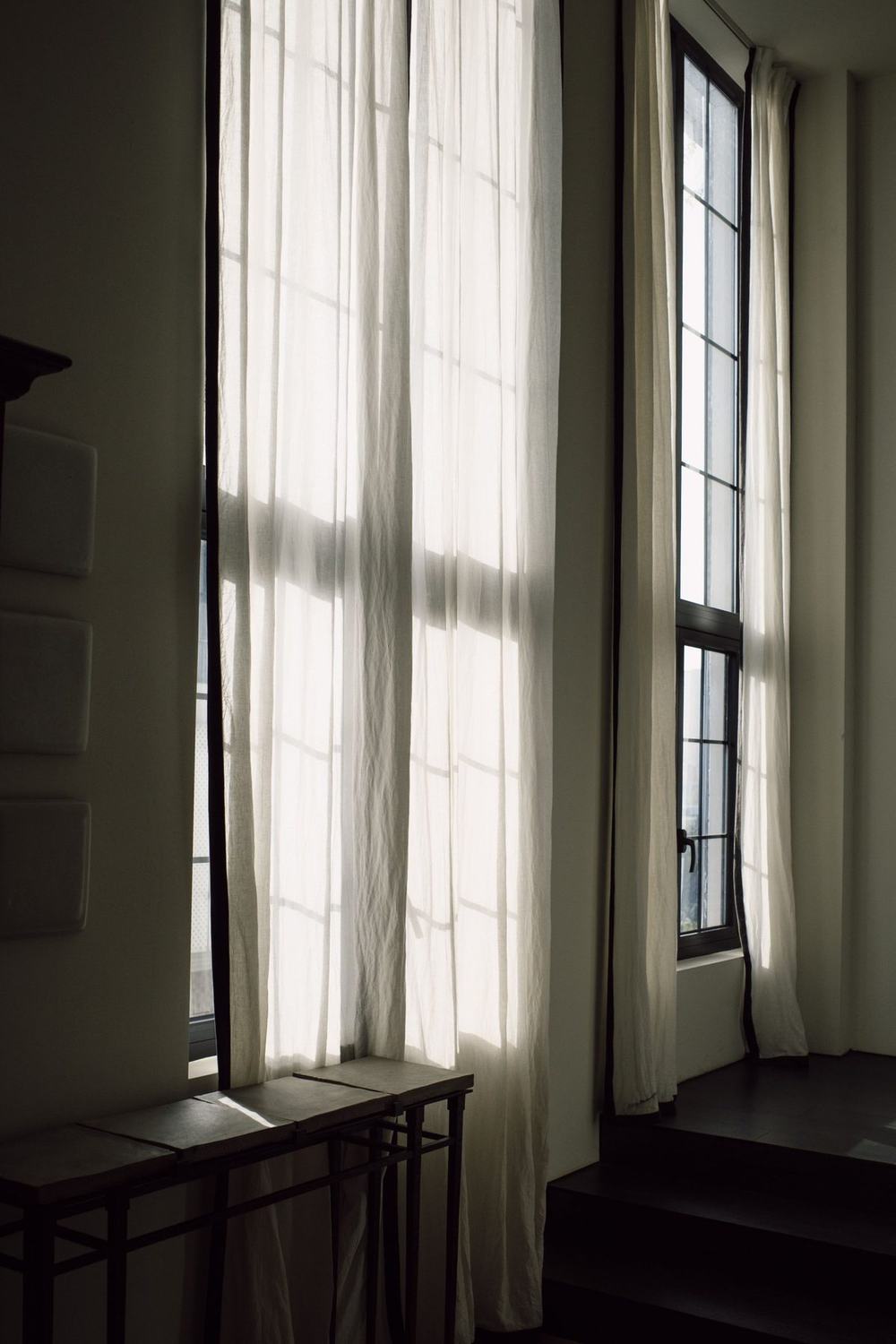 Sunlight coming through long white curtains into a dark room