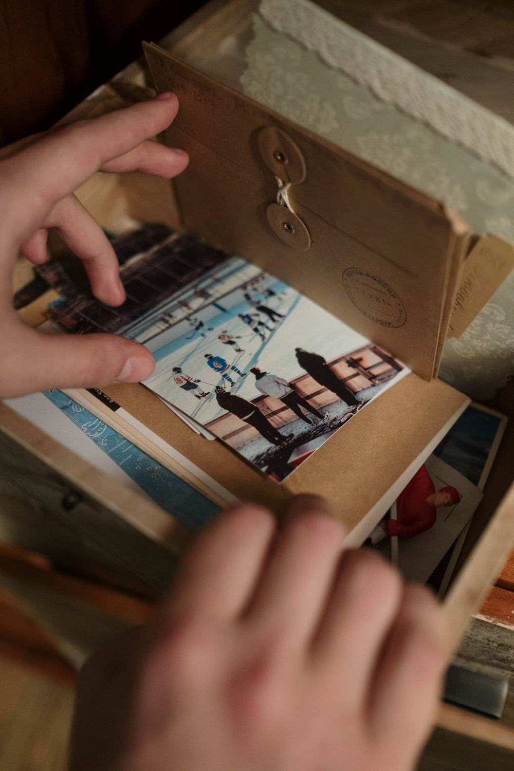 Hands opening a box of old photos and envelopes kept as memories