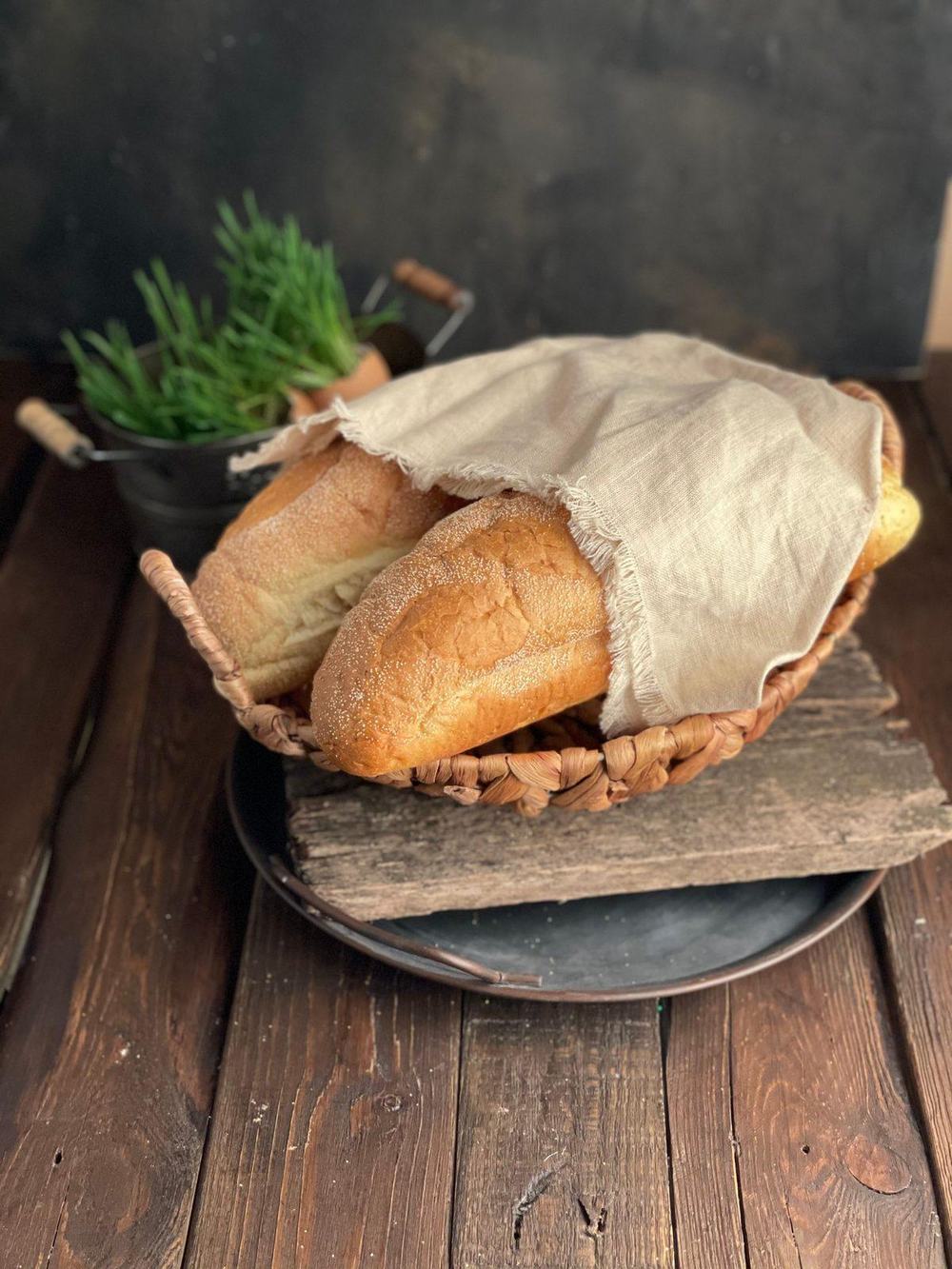 Crusty bread covered with natural linen in a woven basket on a rustic table