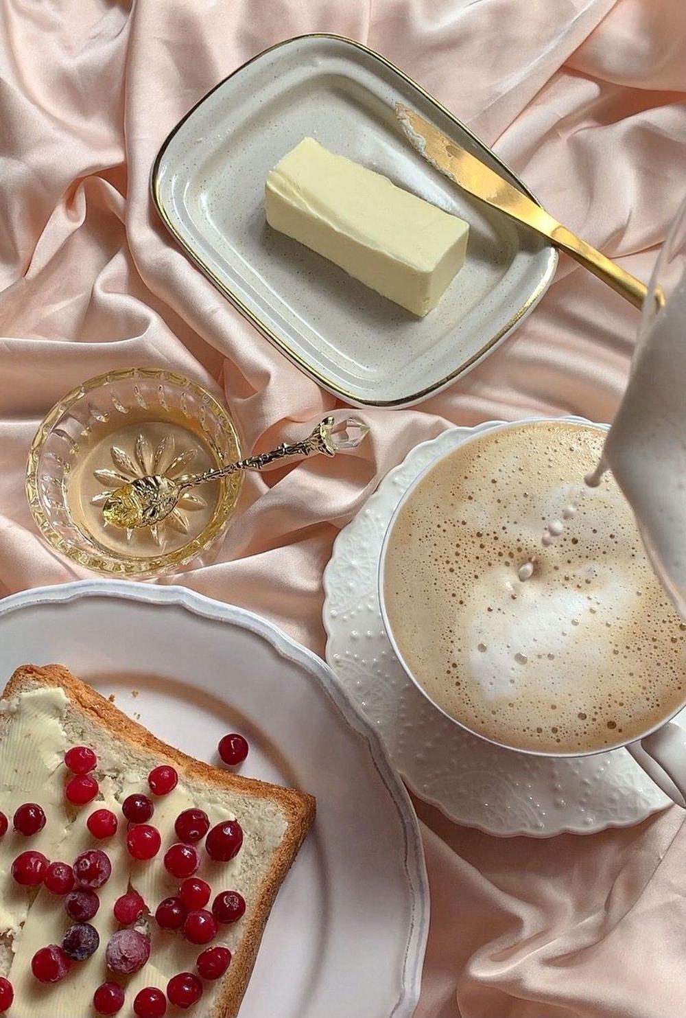 Slow breakfast with soft butter, coffee, honey and toast with cranberries on pink satin