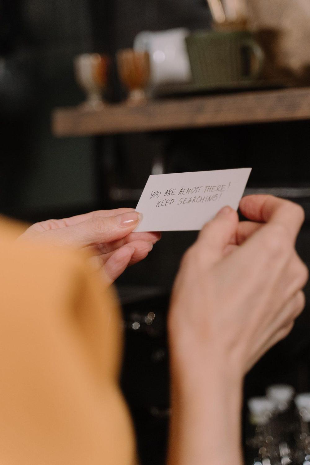 Hands holding a small handwritten note with an encouraging message