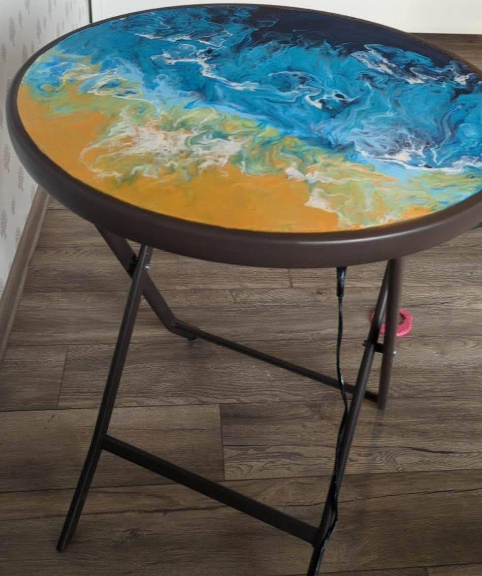 A small round table with a poured top like the sea meeting the sand