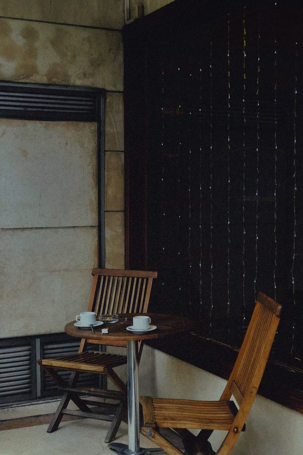 An empty café corner with two wooden chairs and two finished cups