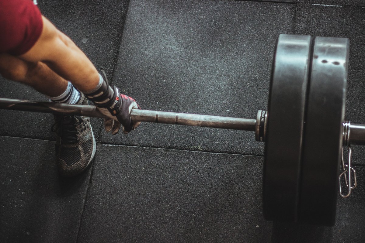 Hands gripping a heavy barbell on a dark gym floor