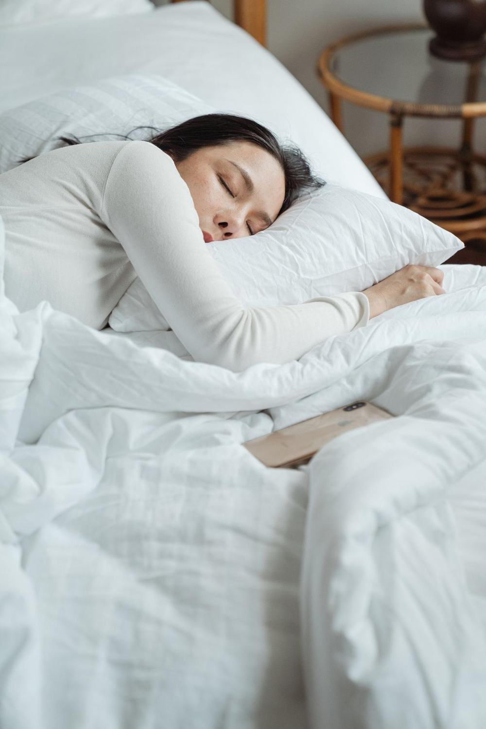 A woman sleeping peacefully in white bedding