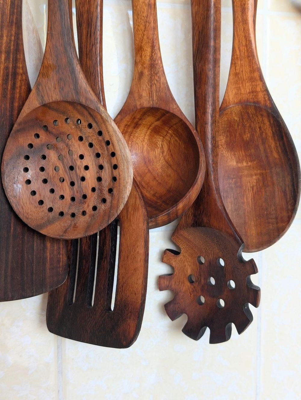 Set of brown wooden cooking utensils hanging on a tiled wall